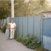 Malvina and her friend's son stand where her store had been, where there is now a blue fence